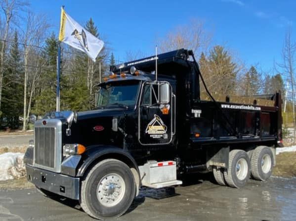 Un camion à benne noir est garé à côté d'un drapeau