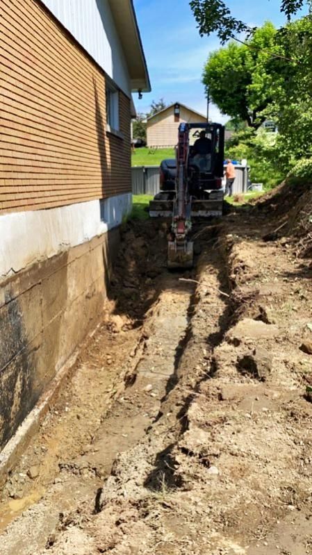 Un bulldozer creuse un trou devant une maison.