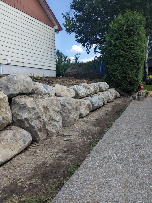 Un mur de pierre est en construction devant une maison.