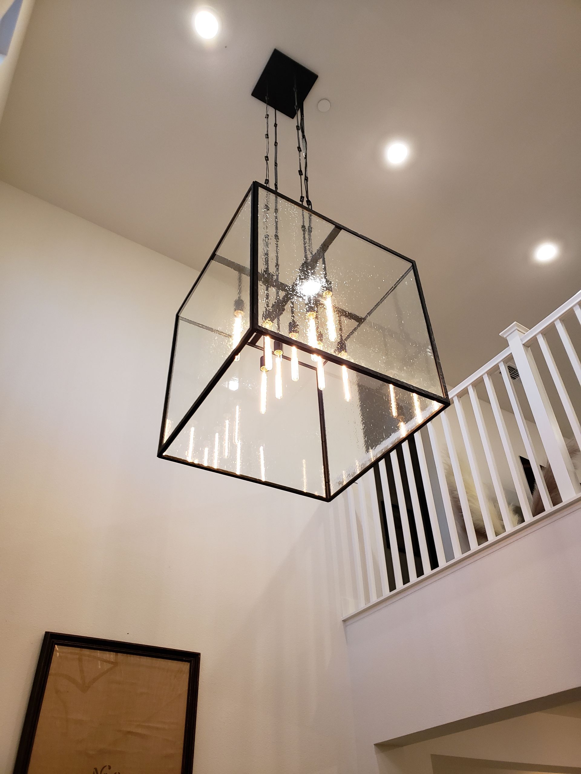 Light fixture installation featuring a modern glass chandelier in residential foyer