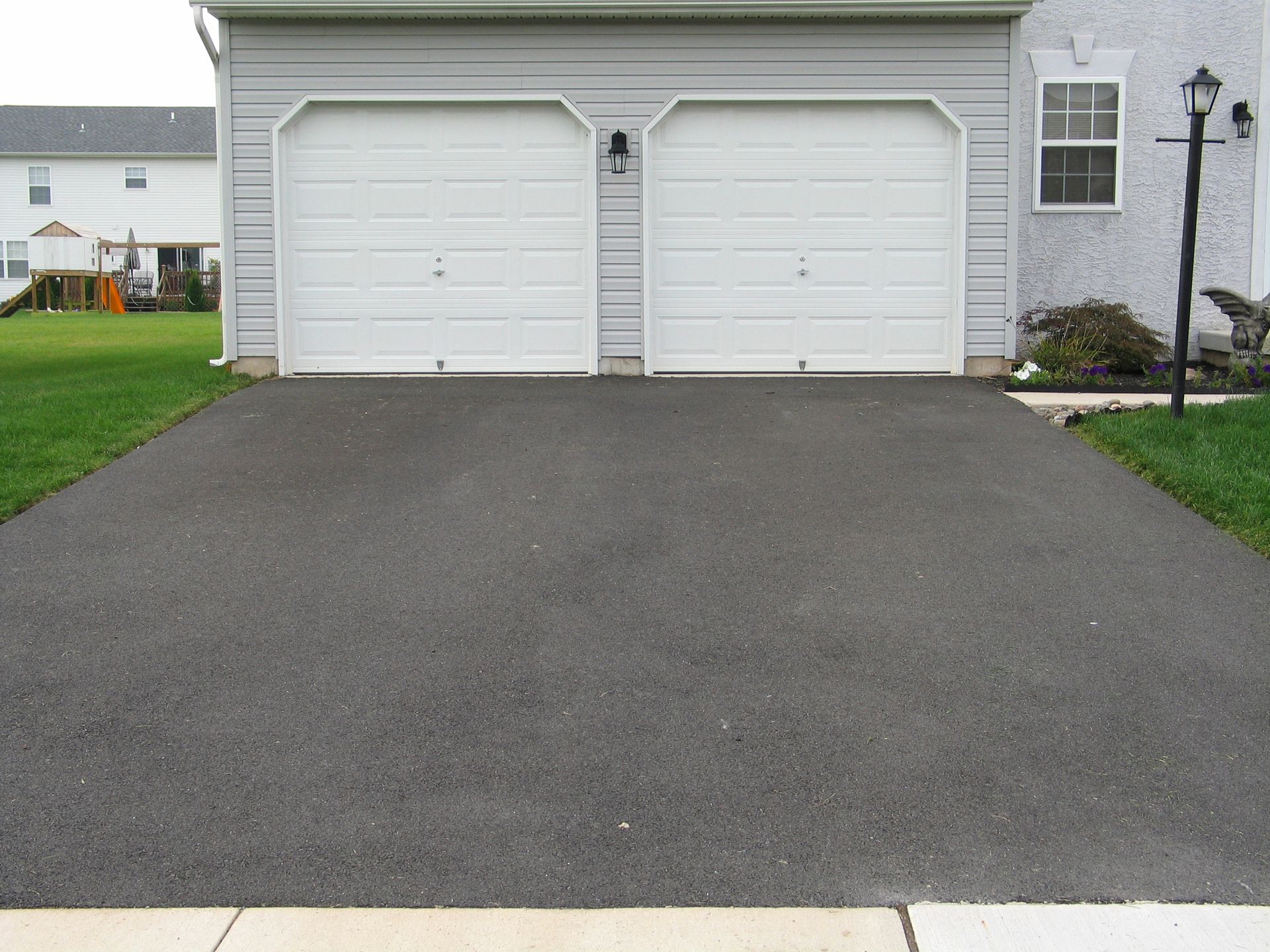 Driveway with two garages and sidewalk, ideal for a residential asphalt contractor.
