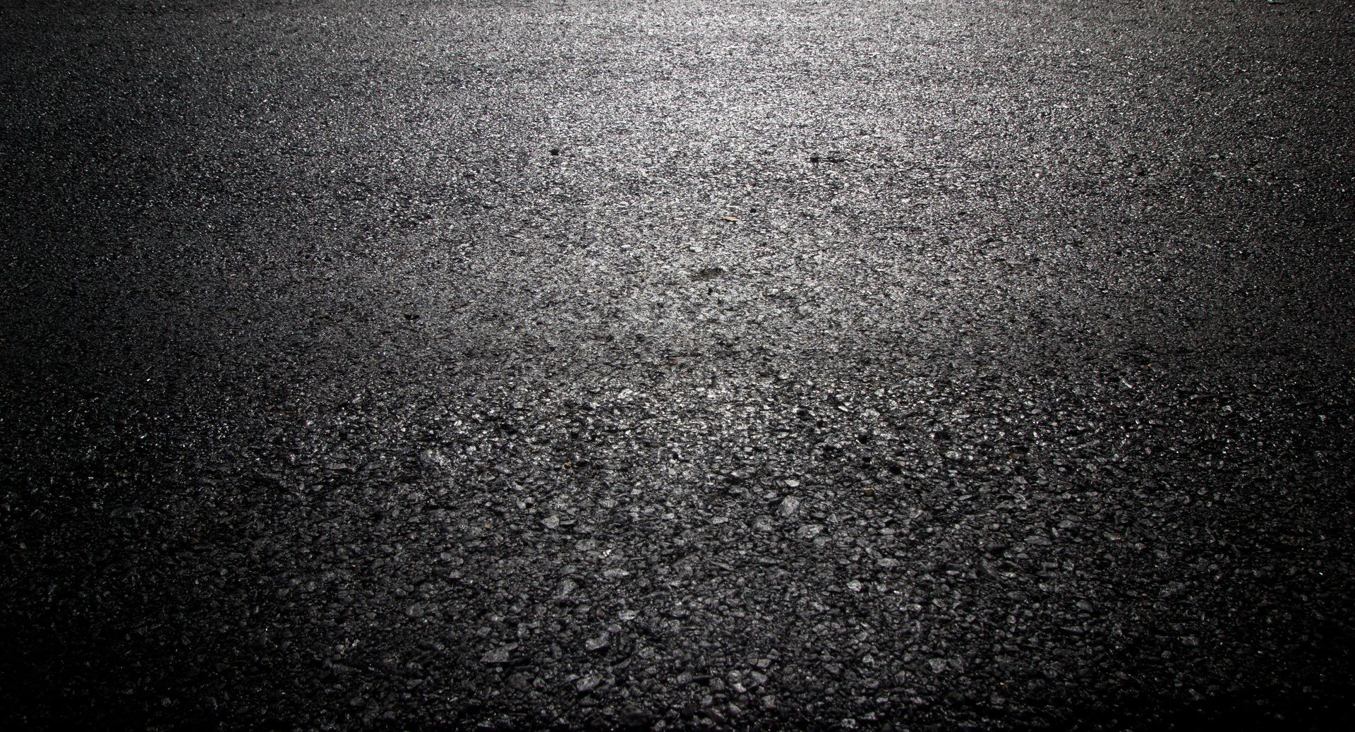 Close-up of freshly sealed driveway by an asphalt driveway contractor, glossy and detailed.