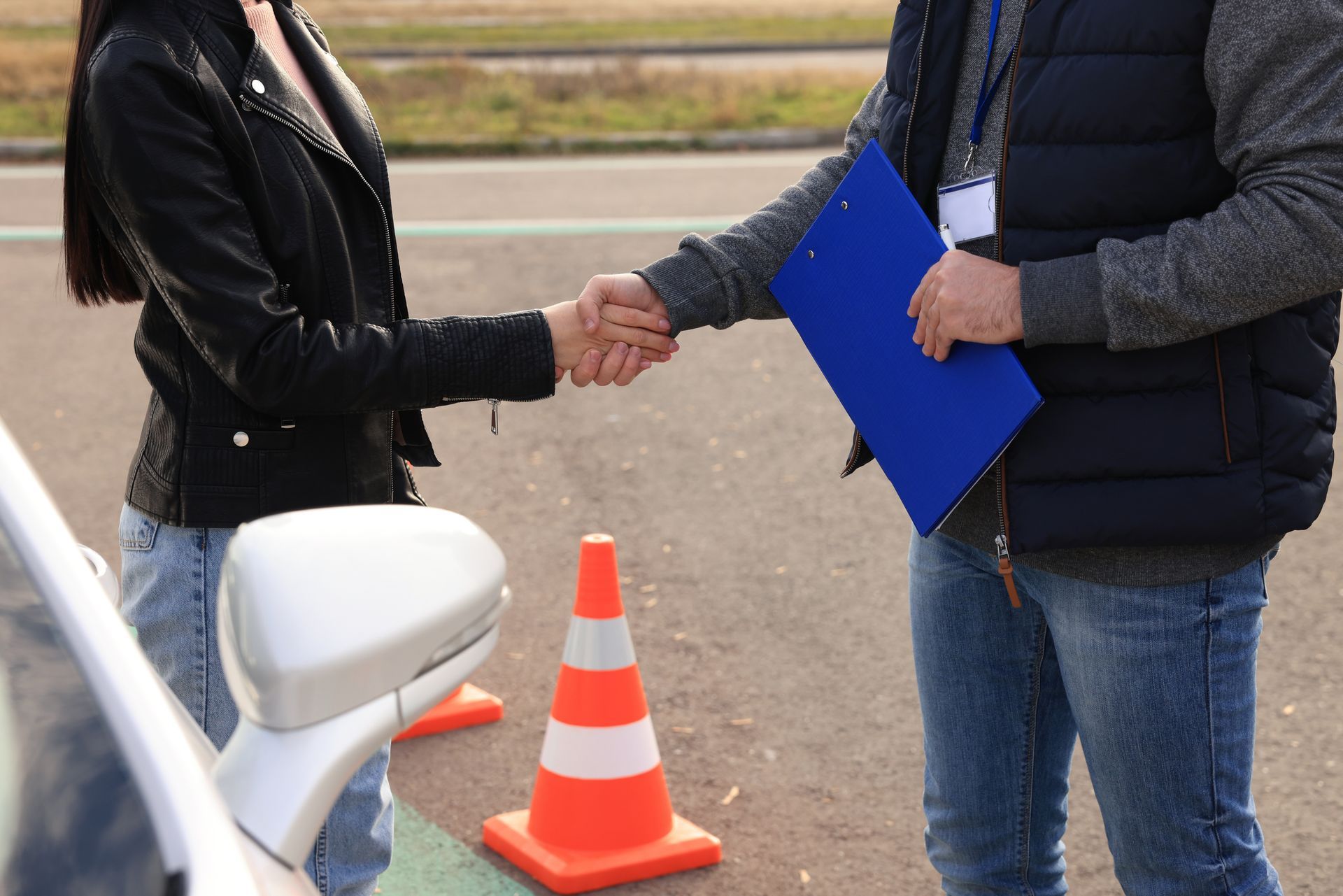 Two workers shaking hands on a newly paved road.