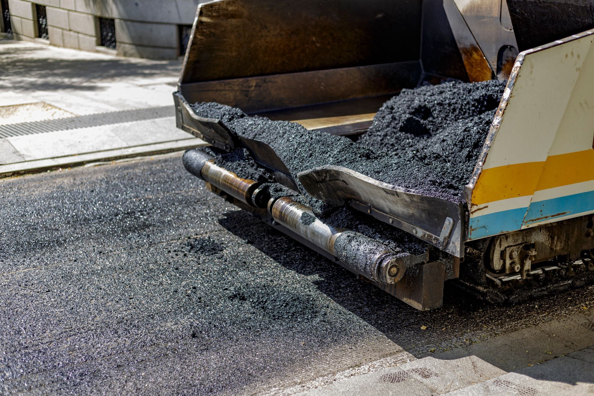 Asphalt Paver spreads asphalt on a road being paved.