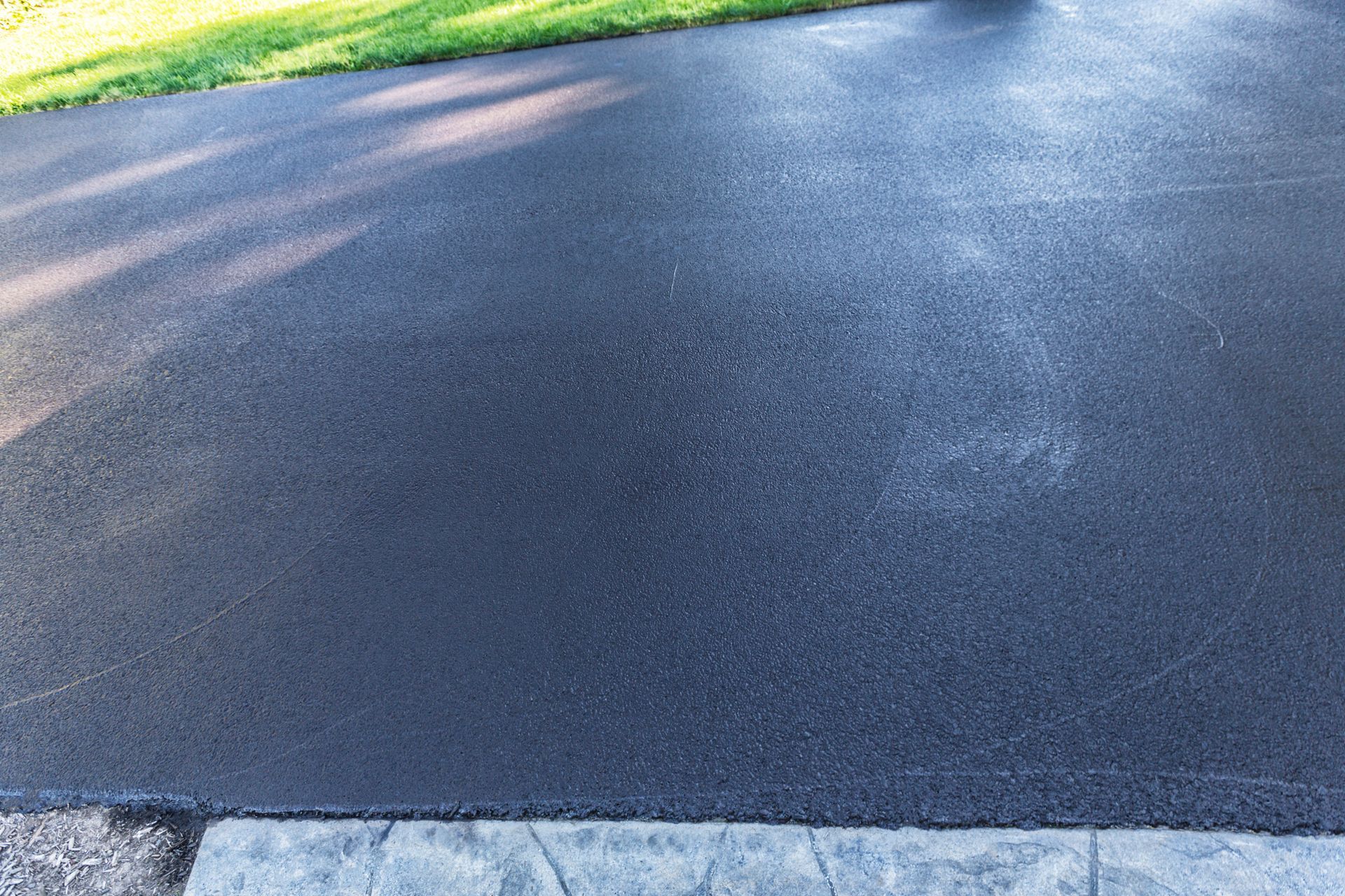 Clean and wet asphalt driveway, the surface of it flat.