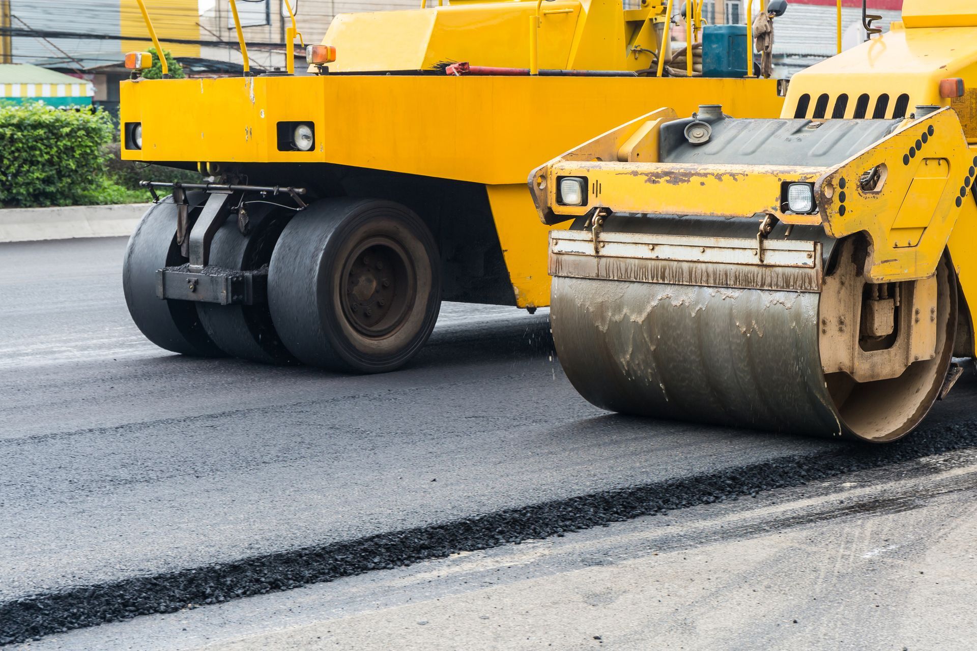 Two yellow road rollers flatten an asphalt mix in a road. Two yellow road rollers flatten an asphalt mix in a road.