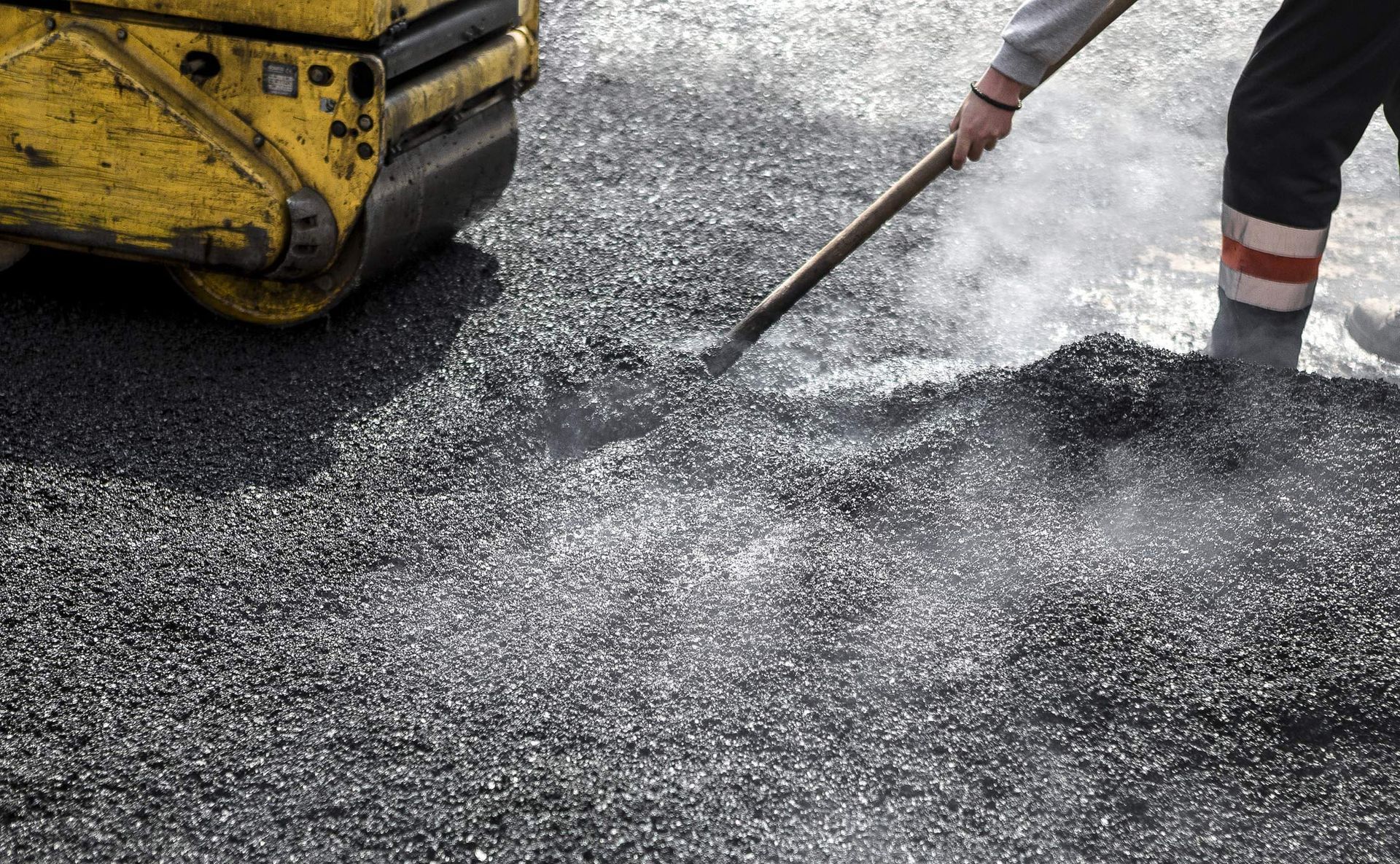 Close-up of an asphalt contractor service with a roller compacting the asphalt on a road.