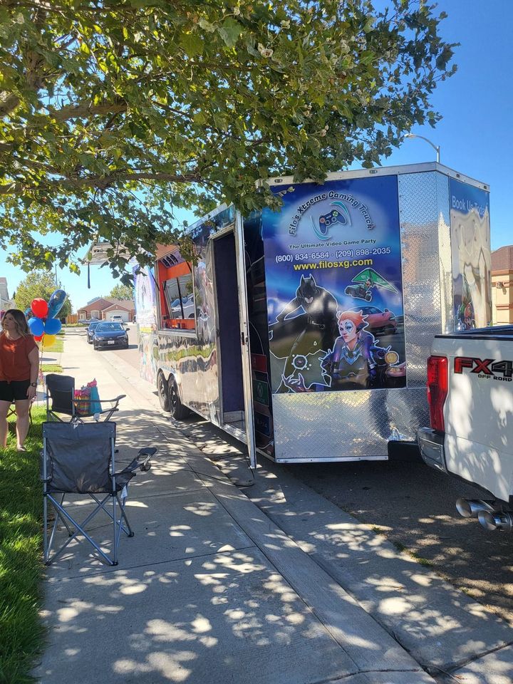 A trailer with a silver exterior and a colorful graphic of characters parked on a sidewalk.