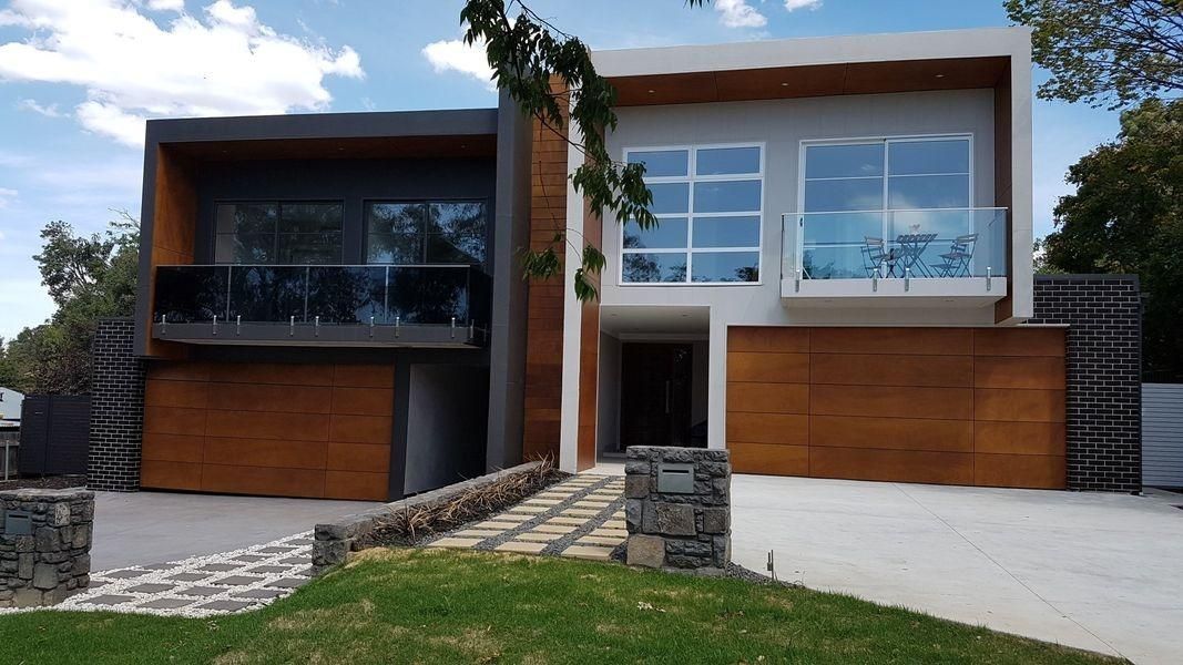 A Large Modern House With A Lot Of Windows And A Large Driveway — The Roller Door Man NQ In Portsmith, QLD