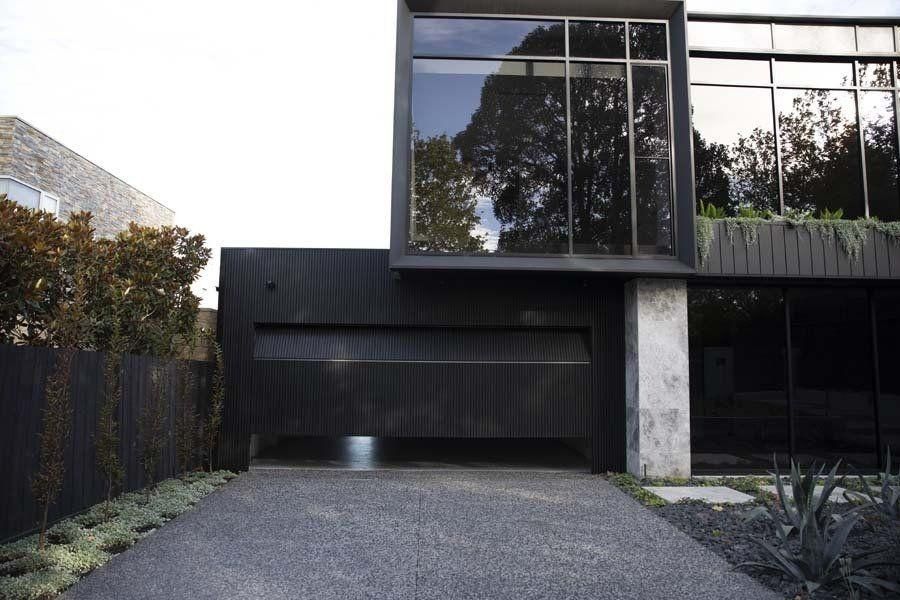 A Black House With A Garage Door And A Driveway — The Roller Door Man NQ In Portsmith, QLD