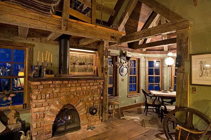 Rustic cabin interior with brick fireplace, exposed wooden beams, and dining area.