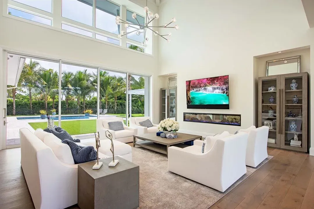 Living room with white sofas, large windows, and a pool view.