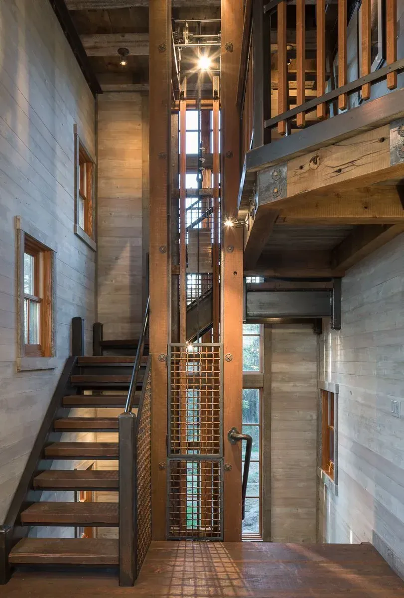 Interior view of a building with a staircase and elevator shaft made of wood and metal.