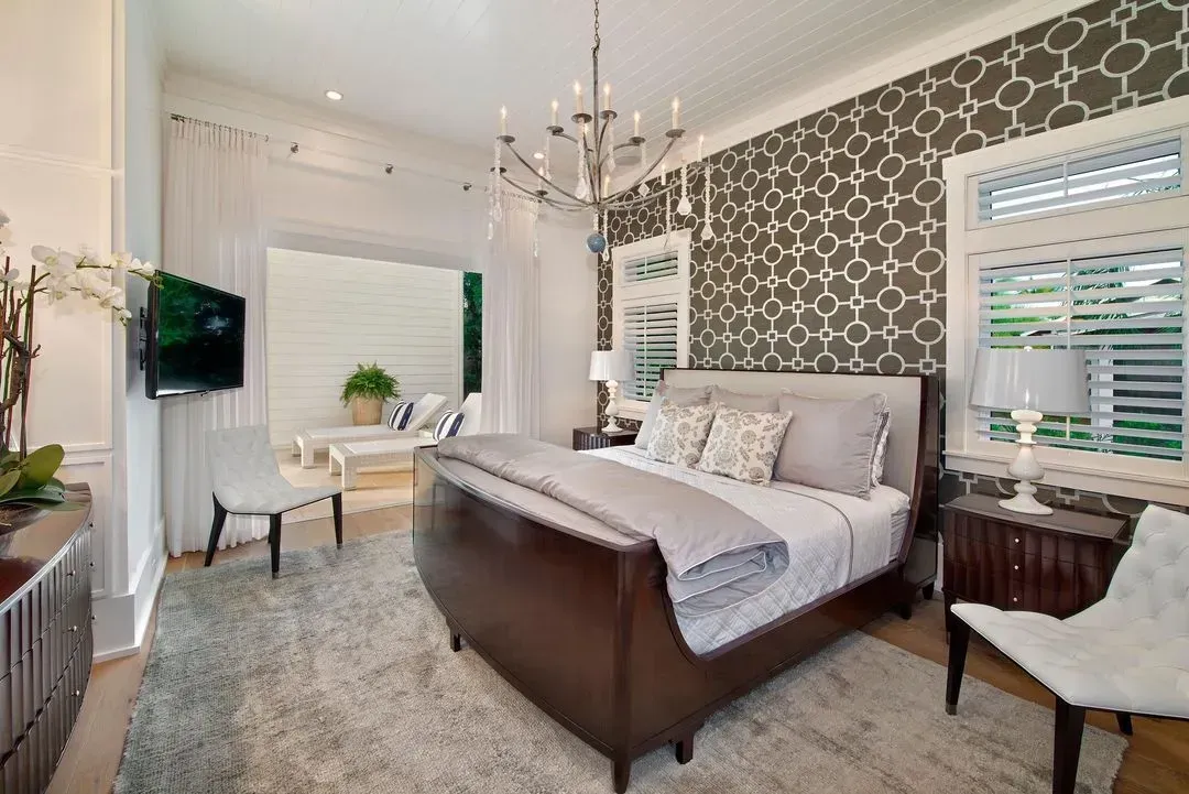 Bedroom with bed, patterned wallpaper, chandelier, and a view to a patio.