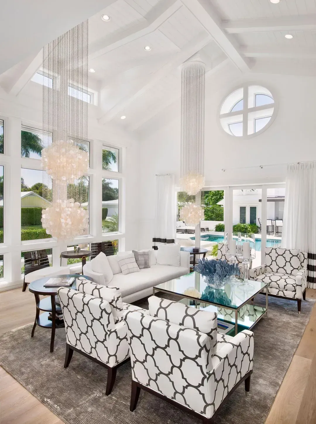 Bright, white living room with high ceilings, large windows, and modern furniture.