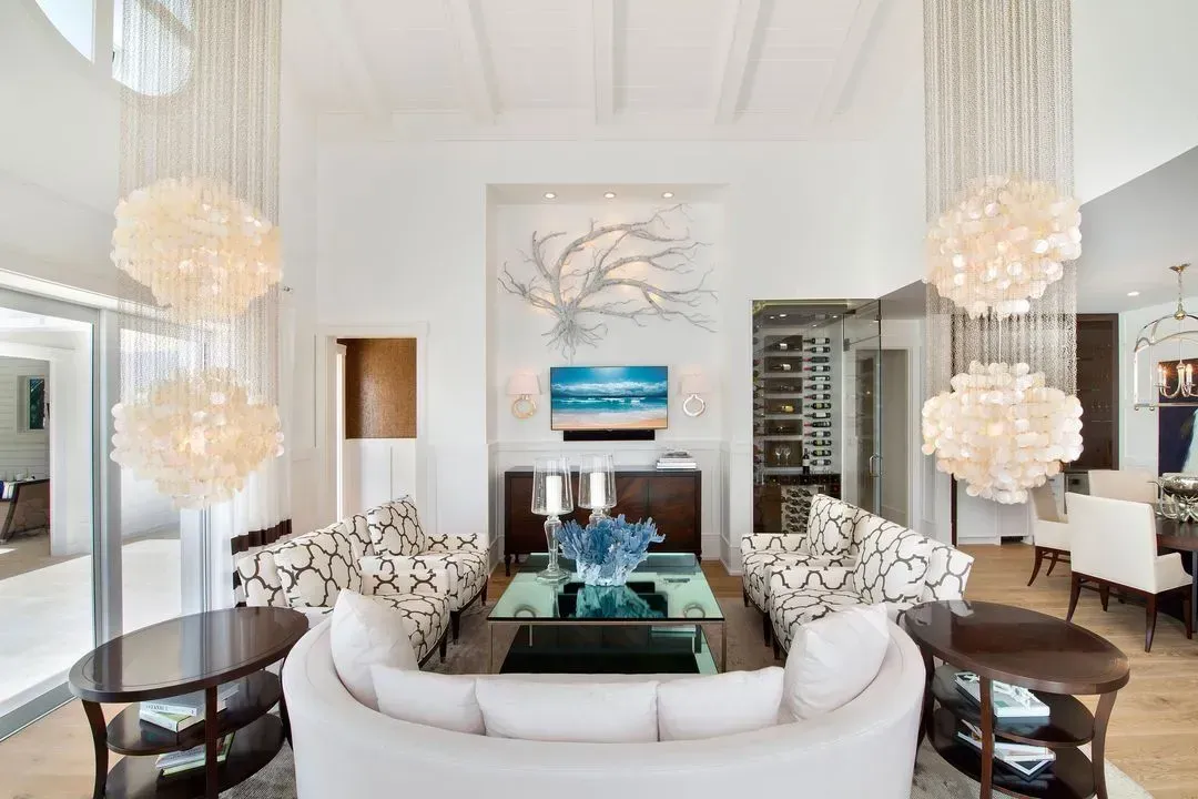 Elegant living room with white walls, shell chandeliers, and a white sofa.