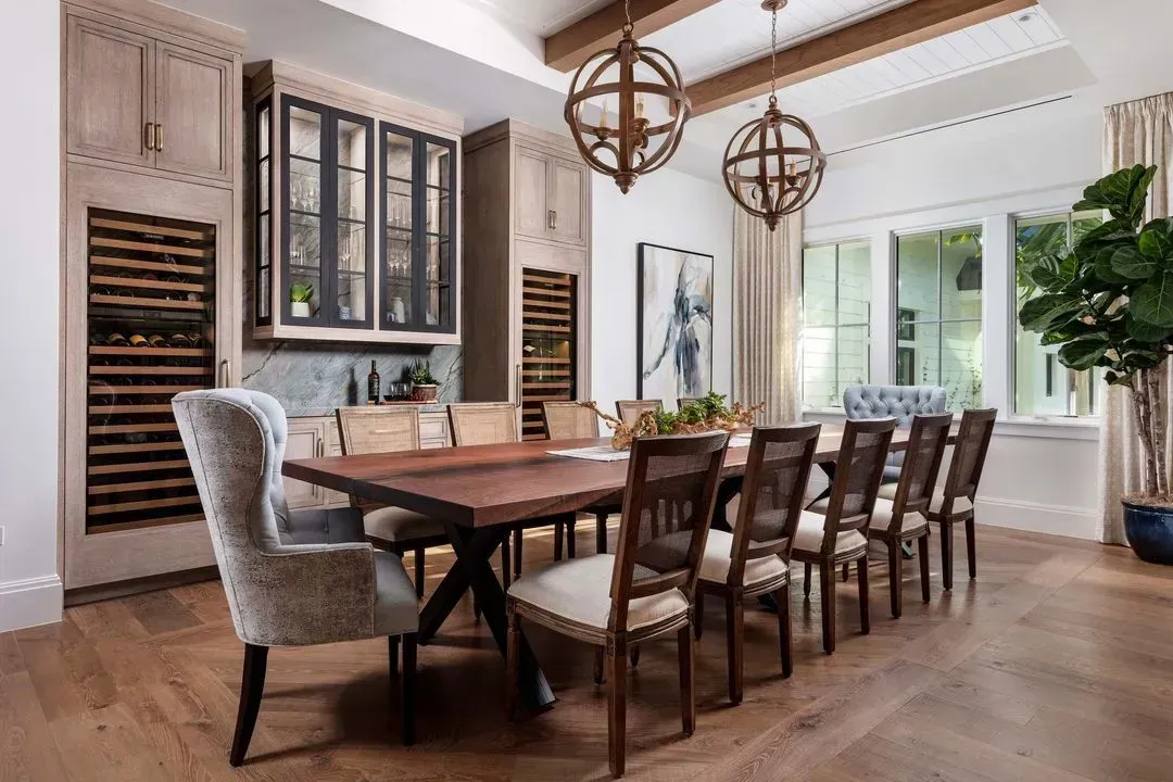 Dining room with long wooden table, chairs, wine storage, and decorative globe lighting.