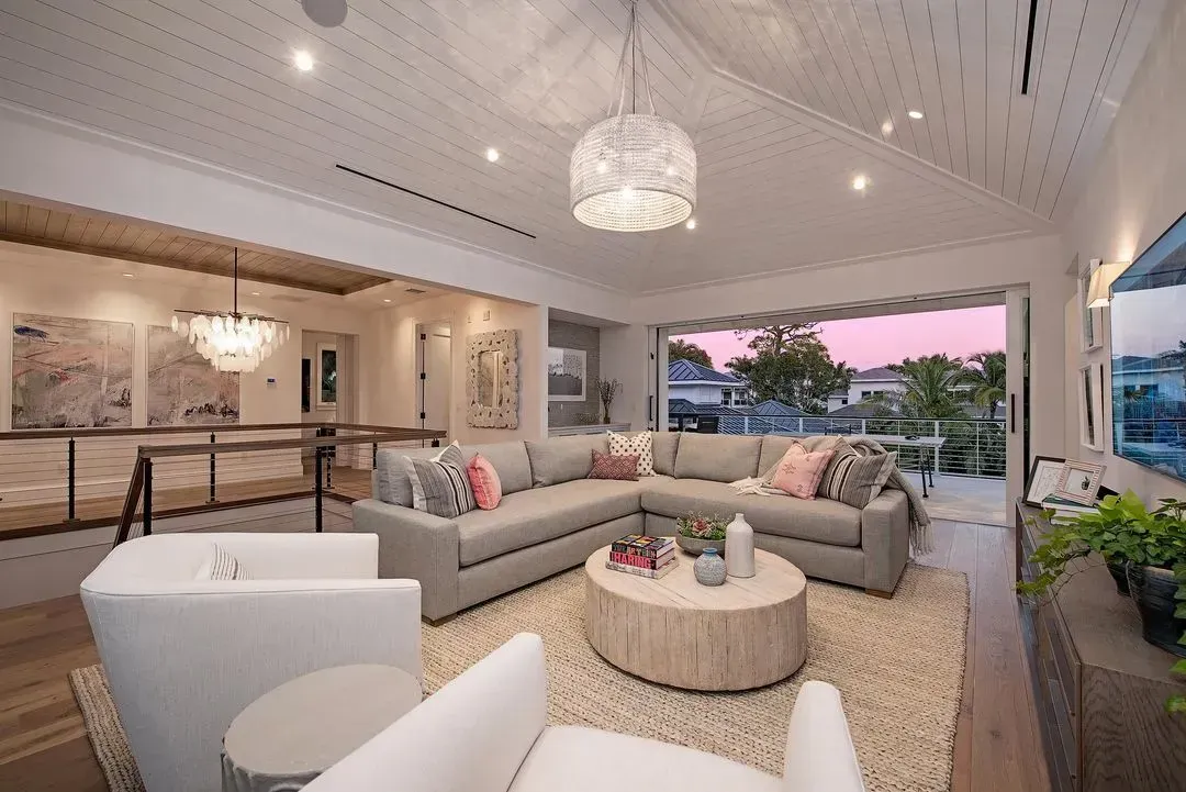 Living room with sectional sofa, coffee table, and open doors to water view.