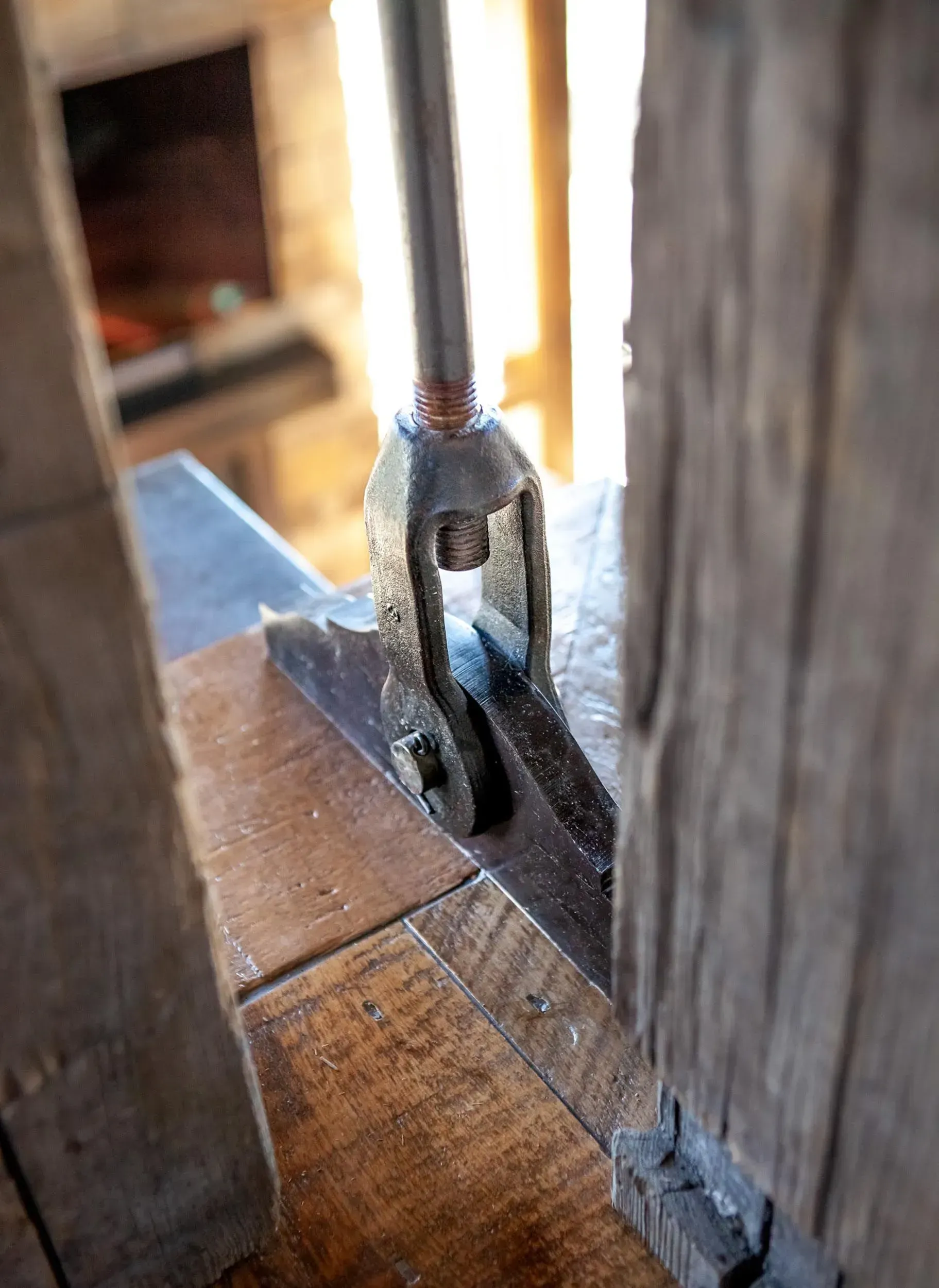 Metal rod and bracket bolted to wooden beams.