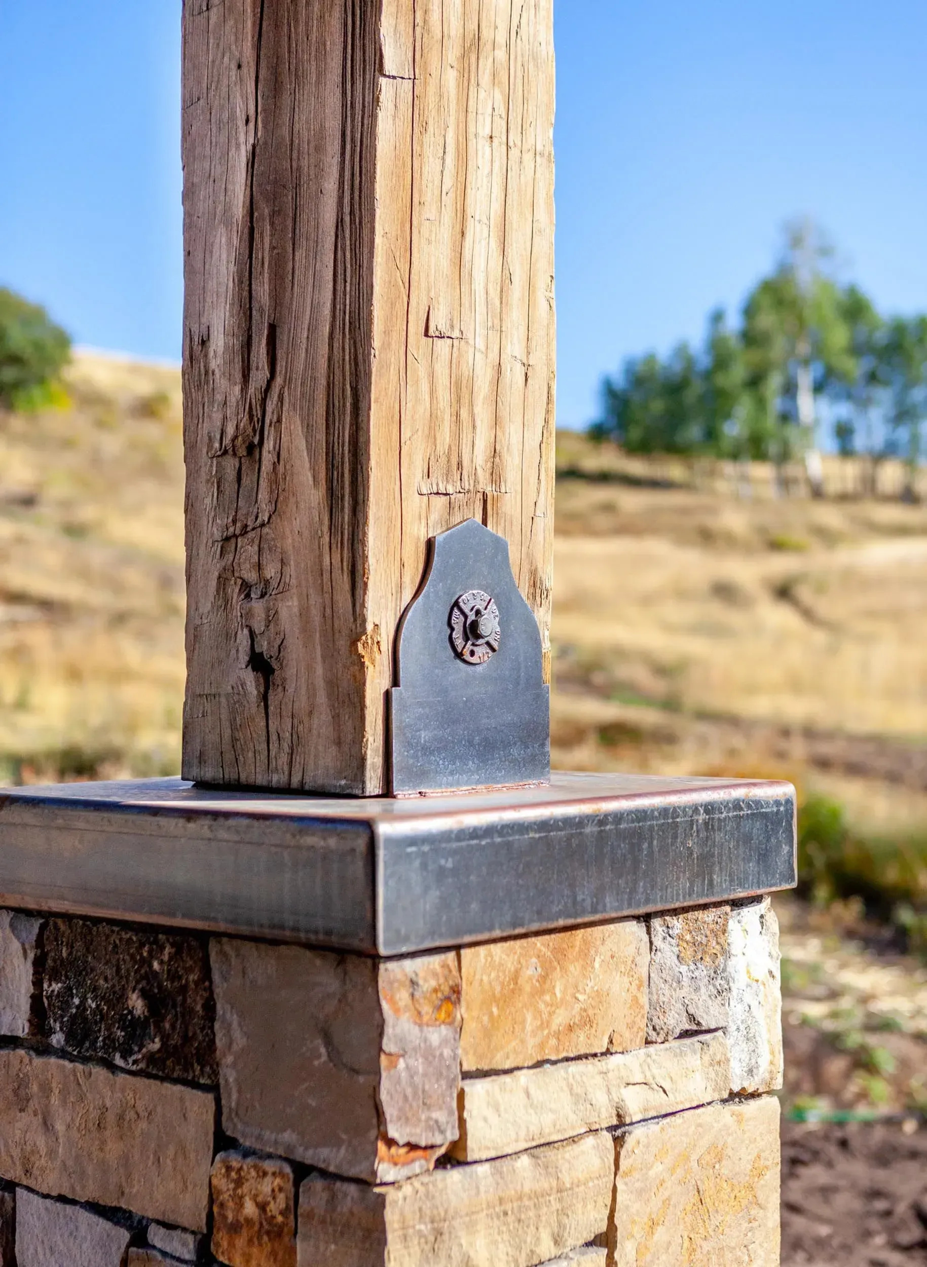 Wooden post with metal bracket on a stone base, set in a natural, outdoor environment.