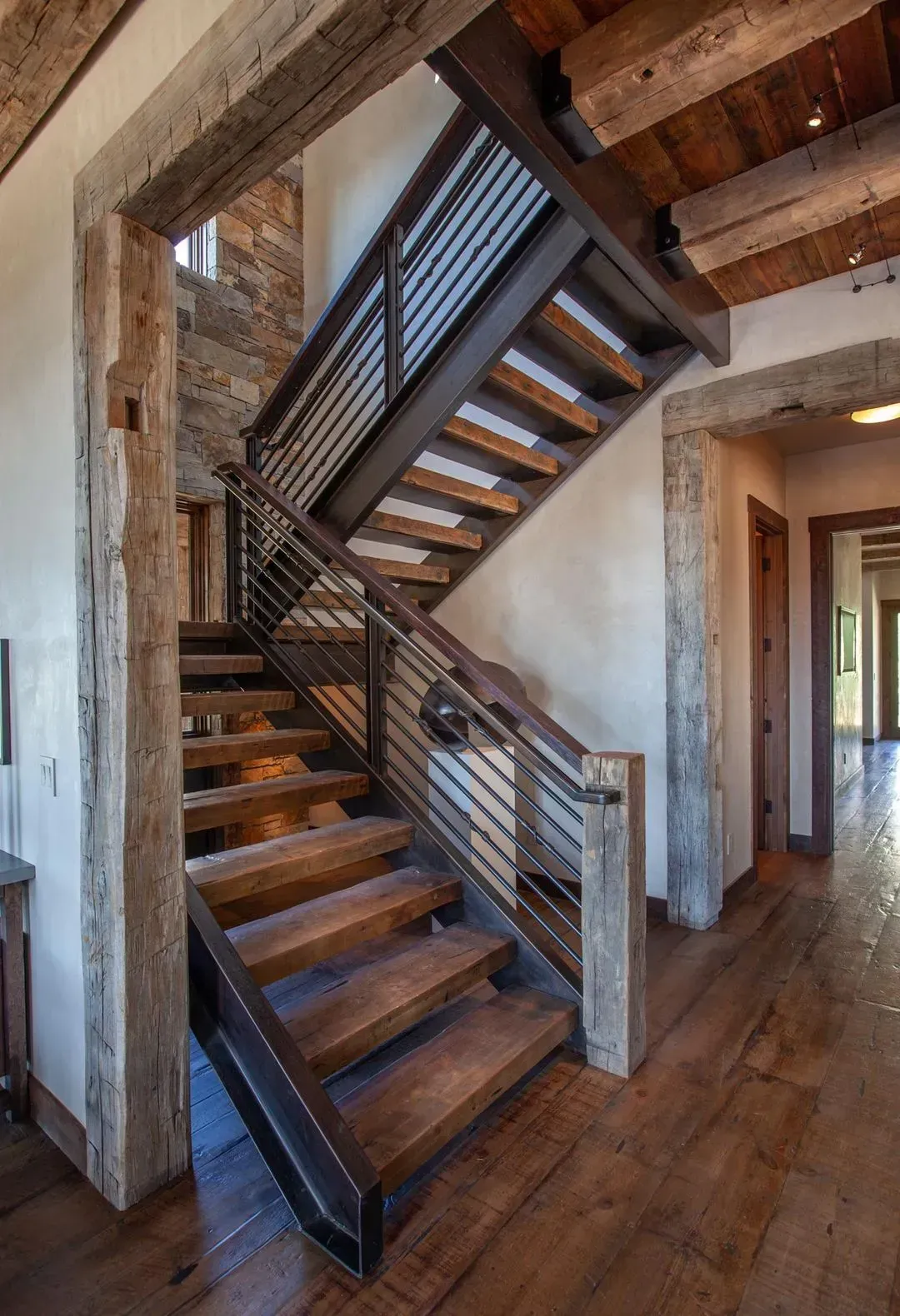 Wooden staircase with metal railings in a rustic-style home.