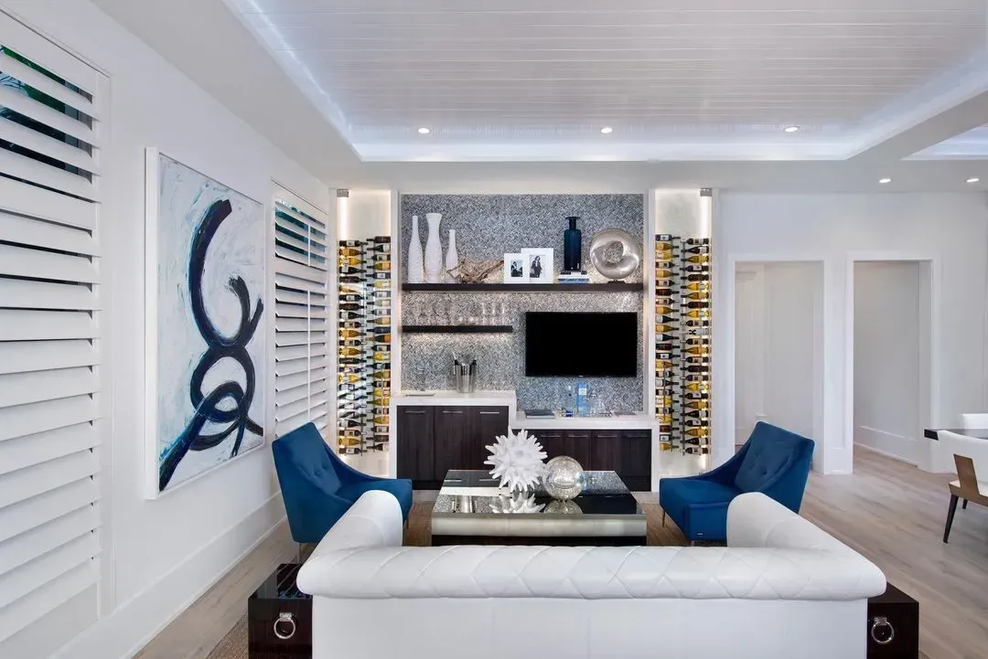 Living room with white sofa, blue chairs, built-in entertainment center, and abstract art.