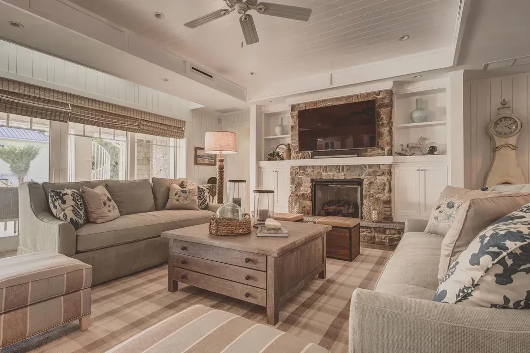 Living room with neutral tones, stone fireplace, two sofas, and wooden coffee table.