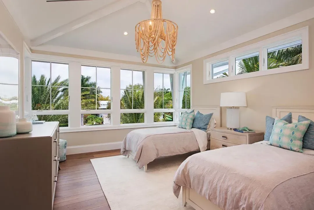 Bedroom with two twin beds, large windows, and a decorative chandelier.