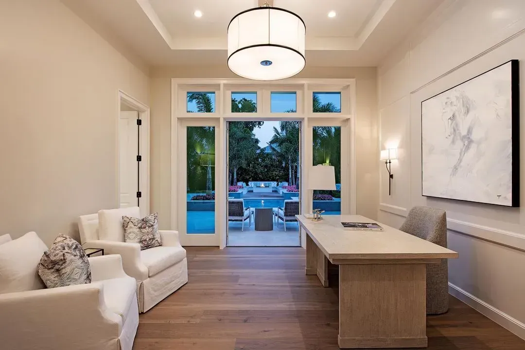 Office with pool view: Desk, chairs, large window, wood floor, white walls, and bright overhead light.