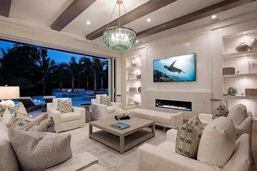Living room with white furniture, fireplace, and open doors to a pool.