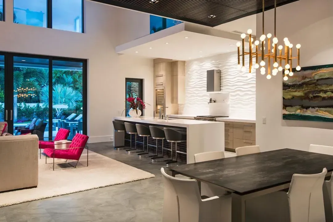 Open-plan living space with kitchen, dining, and seating areas. Bright, modern design with large windows and colorful accents.