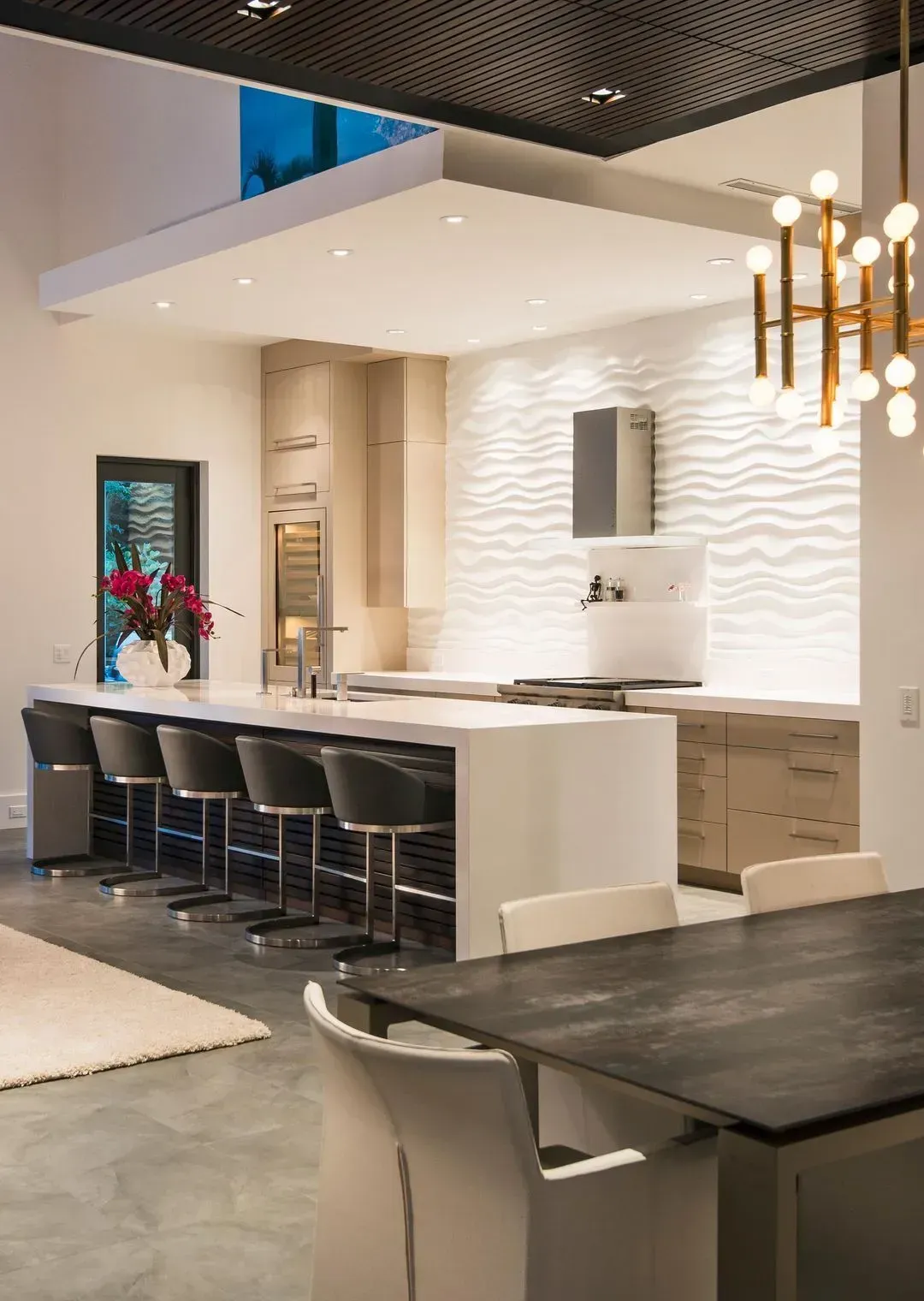 Modern kitchen with a white island, wooden cabinets, and wavy textured wall.