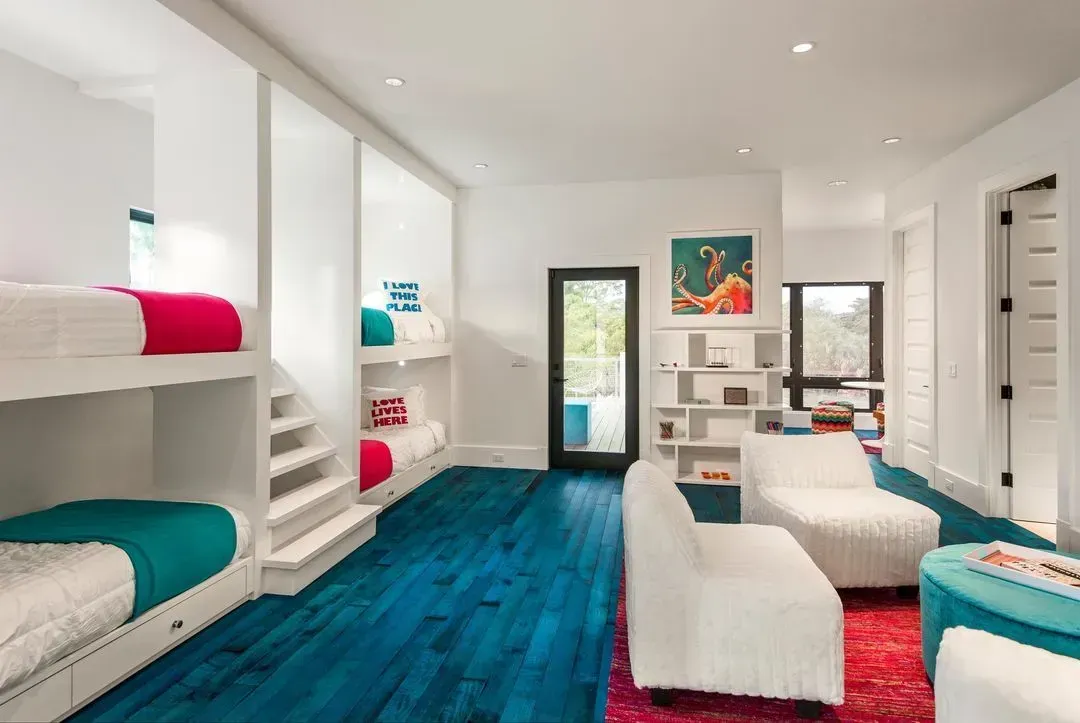 Bedroom with built-in bunk beds, white walls, turquoise floor, and seating area with red rug.