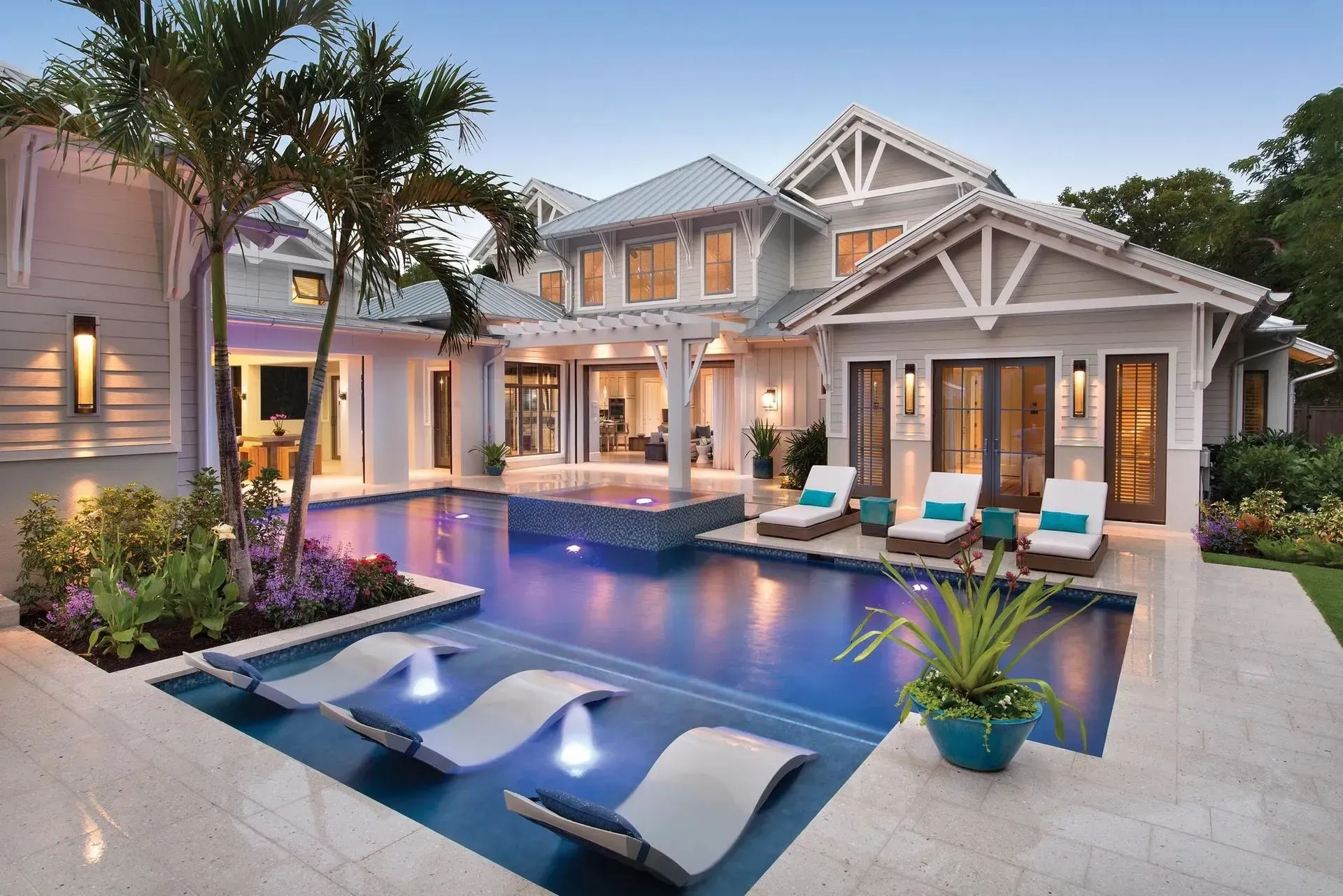 Luxury home with a pool, lounge chairs, and tropical landscaping.