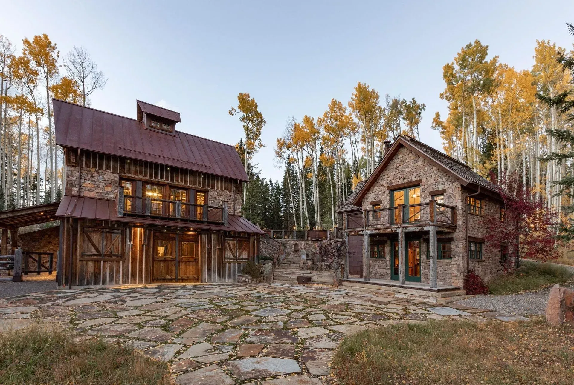 Rustic stone and wood buildings with metal roofs in a wooded setting.