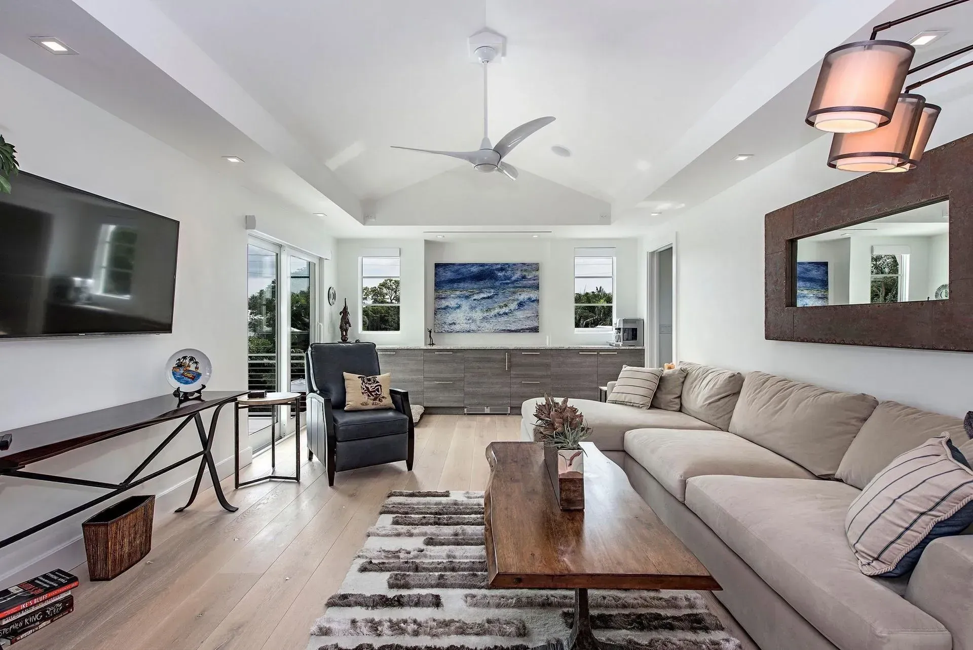 Bright living room with white walls, a sectional sofa, a coffee table, and a large television.