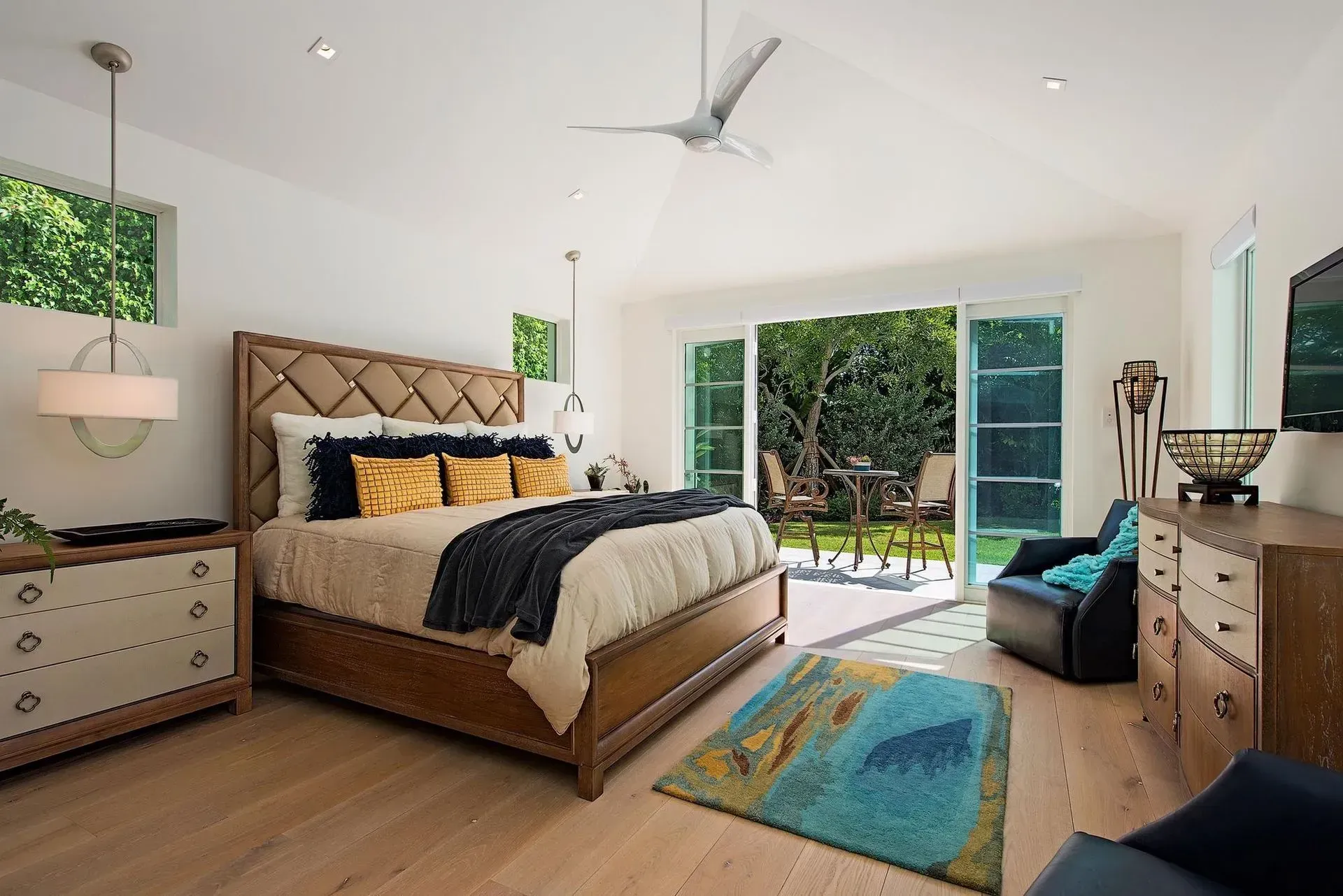 Spacious bedroom with a bed, dresser, and sliding glass doors leading to a patio.