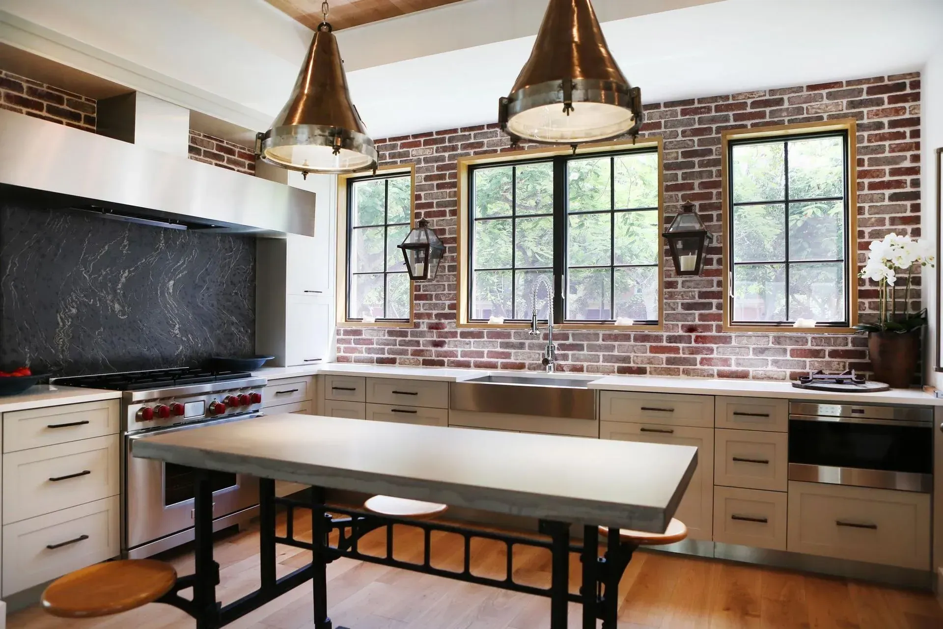Kitchen with brick accent wall, stainless steel appliances, and island with industrial-style legs.