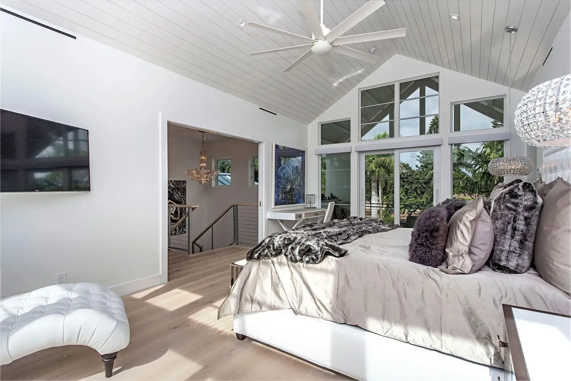 Bright bedroom with large windows, vaulted ceiling, and king bed with plush pillows.