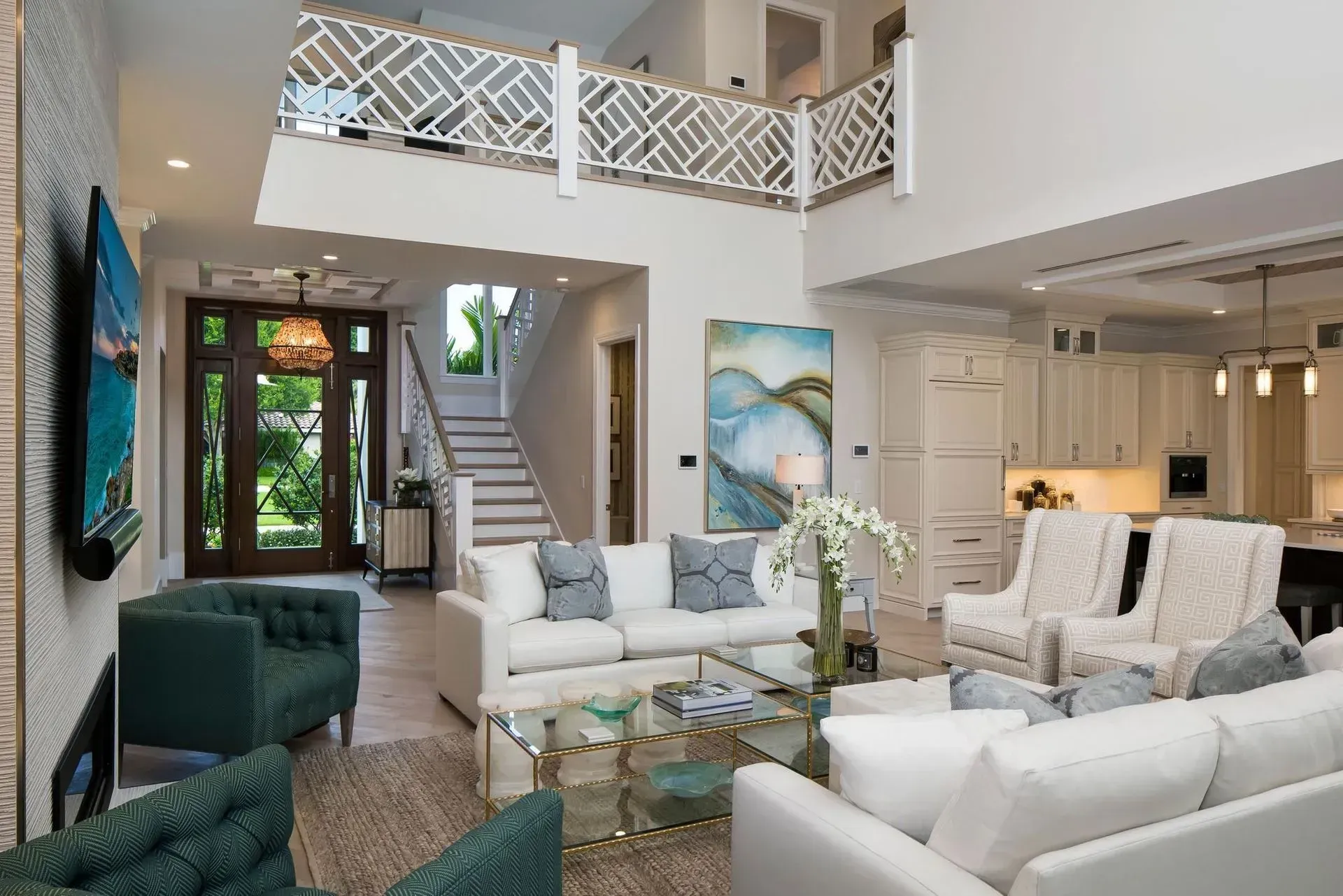 Bright, open living room with white sofas, green chairs, and a staircase leading to a balcony.
