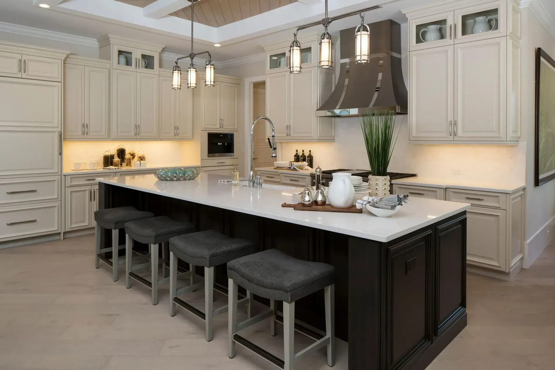 Kitchen with white cabinets, dark island, and bar stools.