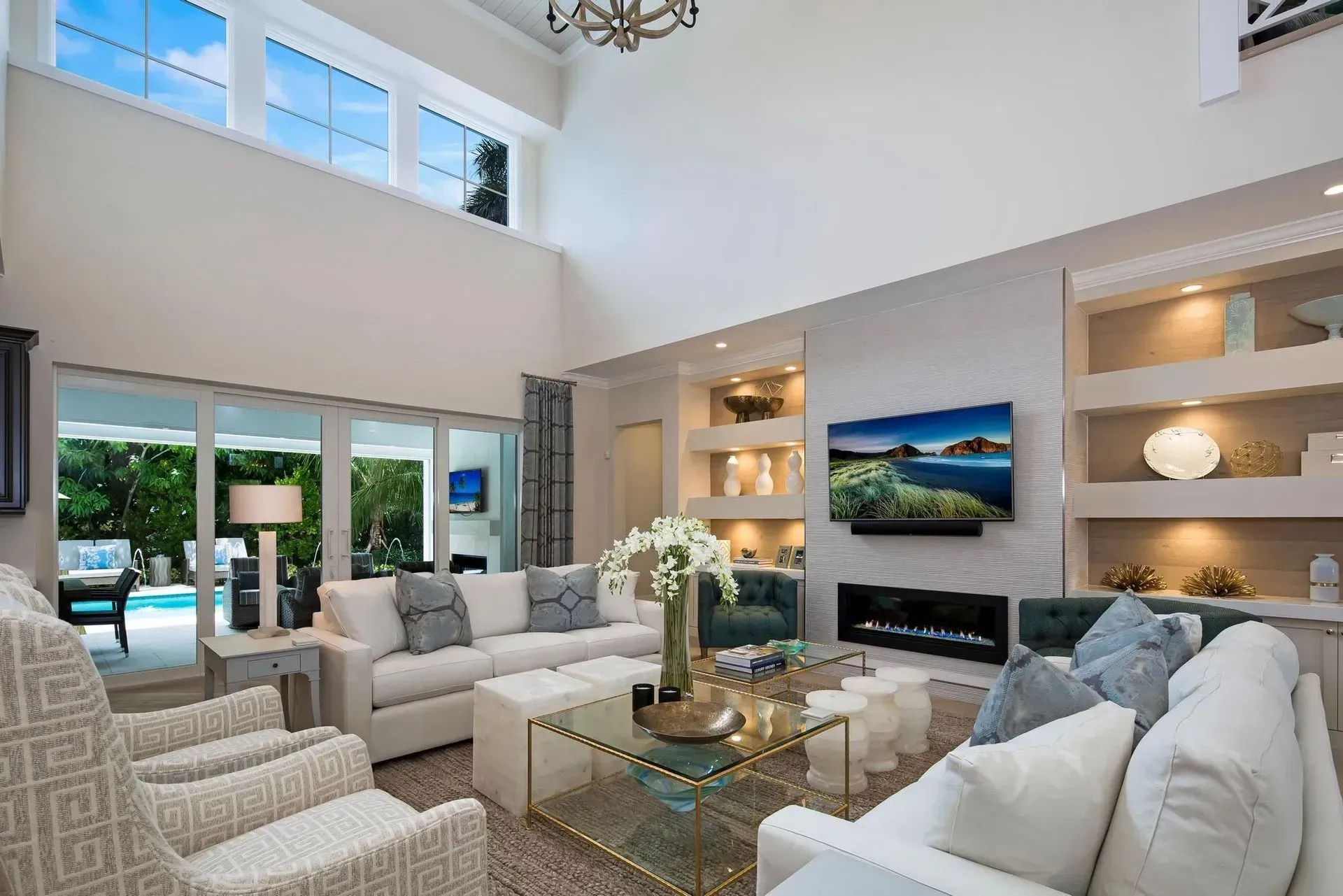 Living room with white walls, sofas, fireplace, and sliding glass doors to a pool.