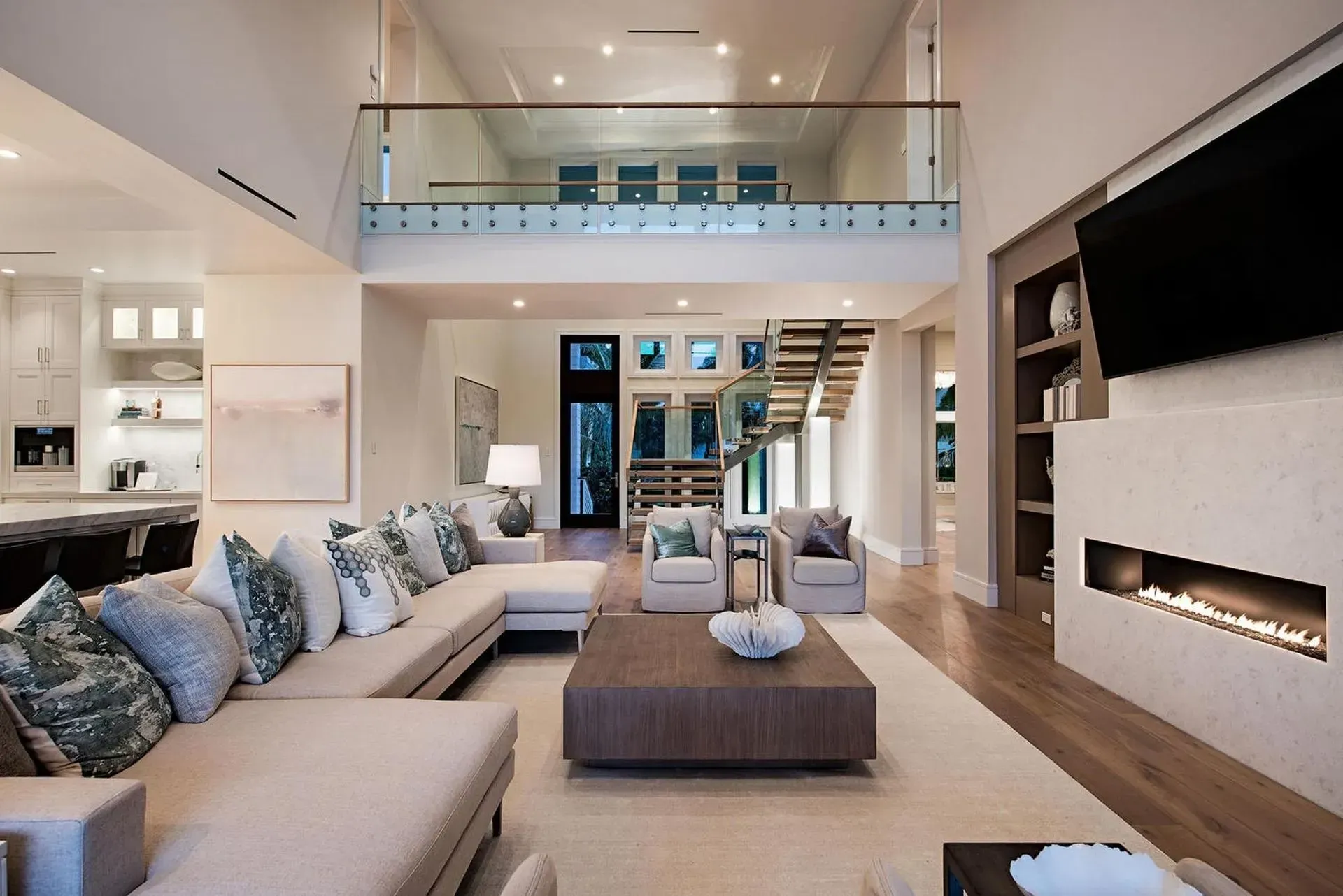 Spacious living room with a sectional sofa, fireplace, and open staircase leading to a loft.