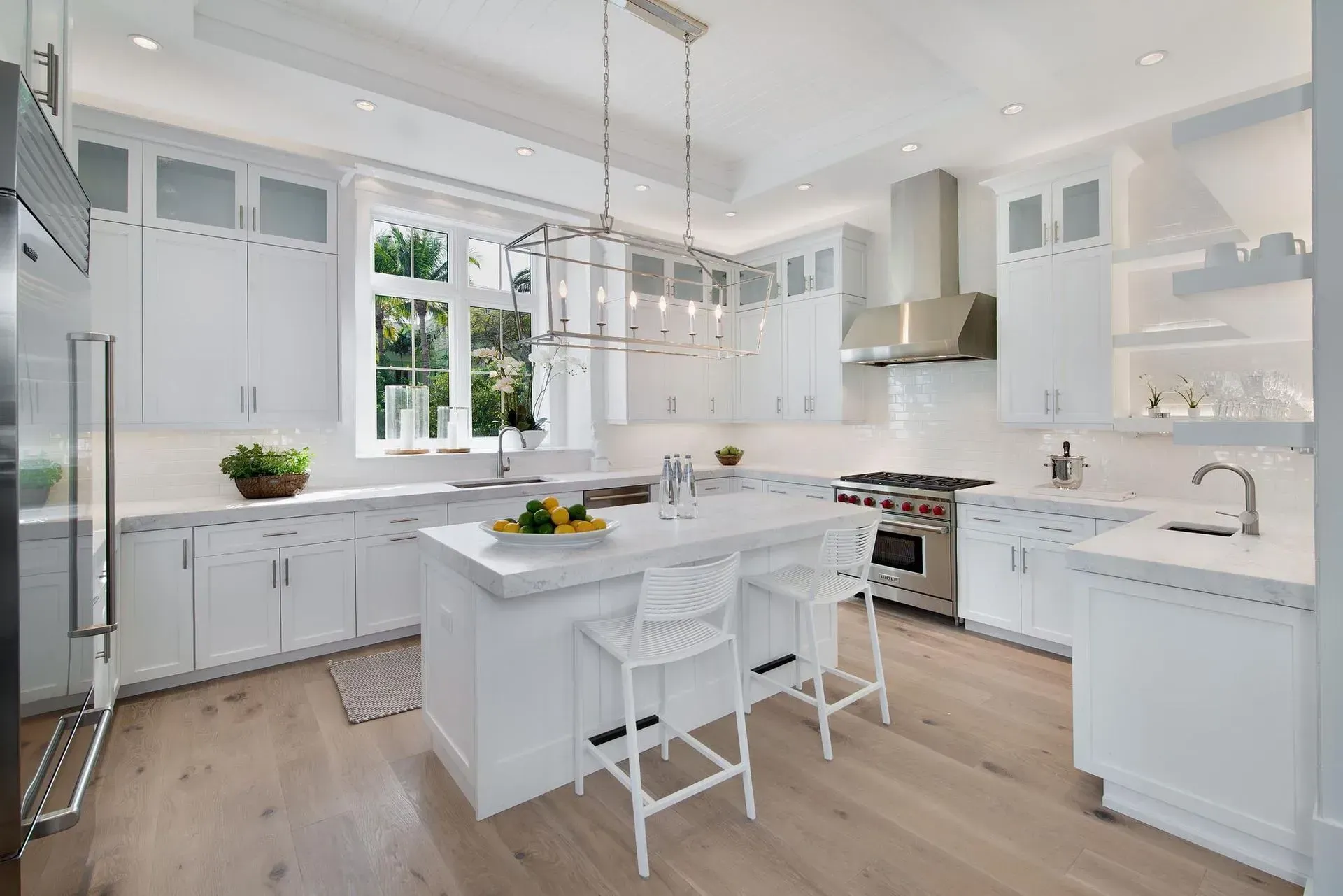 White kitchen with island, cabinets, stainless steel appliances, and wood flooring.
