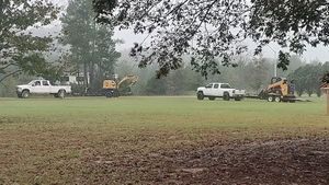 A group of construction vehicles are parked in a grassy field.