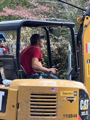 A man is sitting in the driver 's seat of a cat excavator.