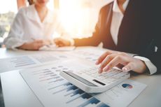 Business meeting with calculator on financial charts and documents