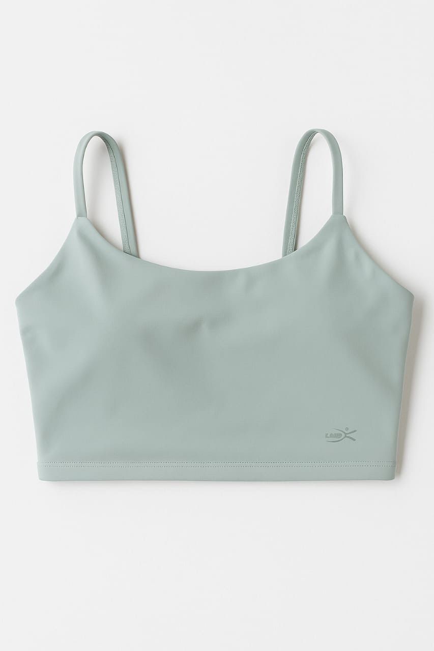 Mujer con top corto verde menta, leggings negros y zapatillas blancas, y con gafas de sol.