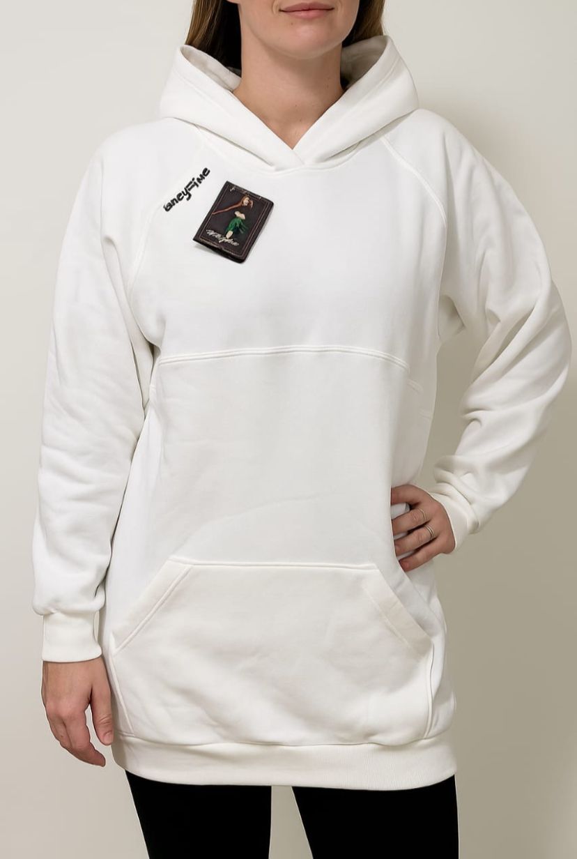 Mujer que lleva una sudadera blanca larga, con la mano en la cadera y una etiqueta en el pecho.