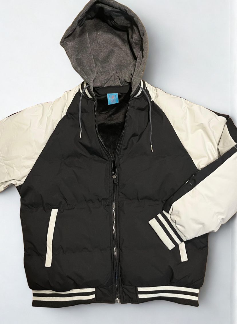 Chaqueta acolchada negra con mangas y capucha grises en una persona.